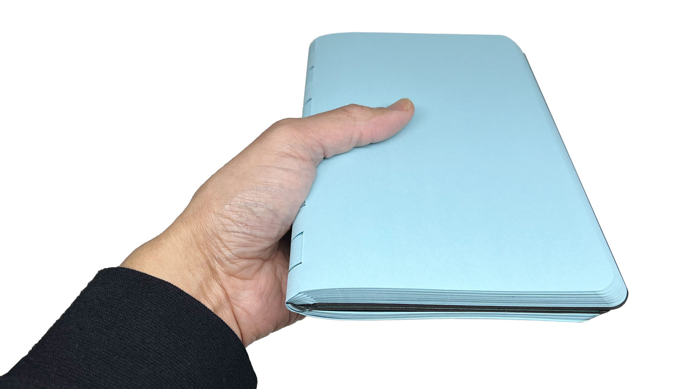 A left hand holding the NUE UX journal by its spine.